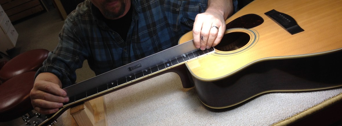 Using a ruler to check the level of frets on an acoustic guitar